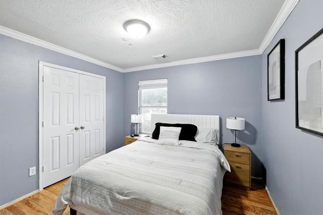 Spacious secondary bedroom with calming blue tones, double-door closet, crown molding, and large window providing abundant natural light. | Image 20