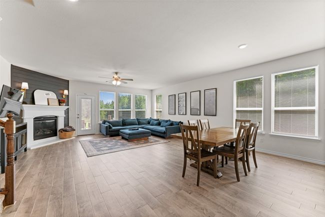 Dining area with wood finished floors, ceiling fan, and a glass covered fireplace | Image 9