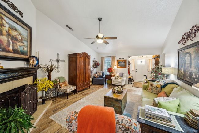 Living room with a ceiling fan, light wood-style floors, high vaulted ceiling, and a fireplace | Image 9