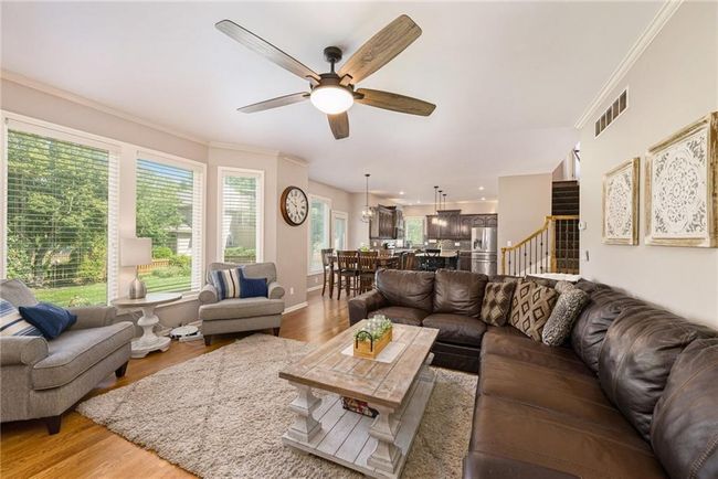Living area with a ceiling fan, crown molding, light wood-style floors, stairway, and baseboards | Image 10