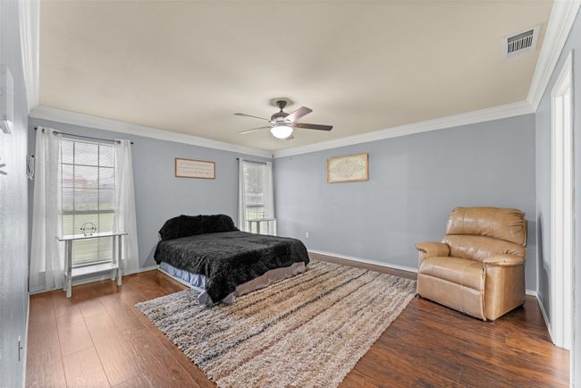 Bedroom with multiple windows, dark wood-style flooring, crown molding, and a ceiling fan | Image 15