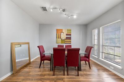 The dining room is bathed in natural light, thanks to a trio of large windows that frame the space beautifully, creating a bright and inviting atmosphere perfect for gatherings or quiet meals. | Image 3