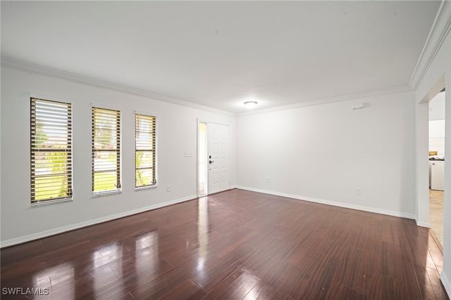 Unfurnished living room with crown molding and wood finished floors | Image 9