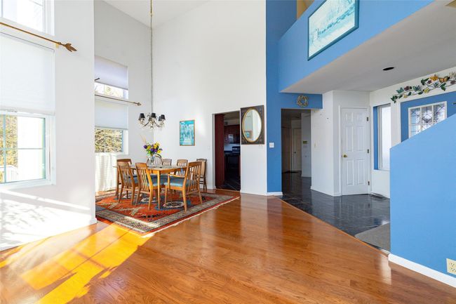 Dining room featuring dark hardwood / wood-style flooring, a towering ceiling, and a chandelier | Image 6