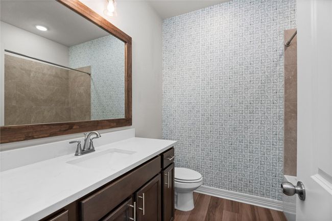 Full bath featuring vanity, toilet, a shower, and wood finished floors | Image 25