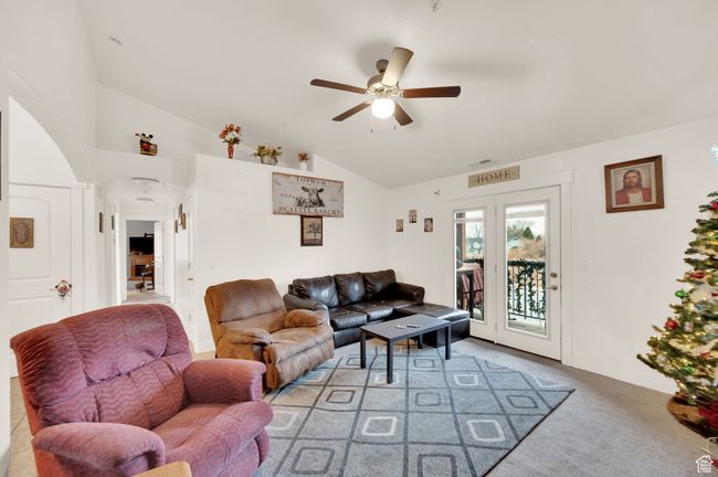 Living area featuring lofted ceiling, ceiling fan, light carpet, and arched walkways | Image 7