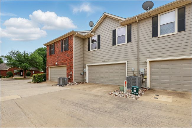 View of property exterior featuring concrete driveway, brick siding, an attached garage, and cooling unit | Image 32