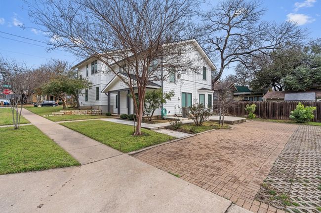 View of front facade featuring decorative driveway, fence, and a front yard | Image 27