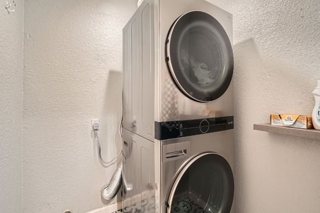 Laundry room with stacked washing machine and dryer and a textured wall | Image 25