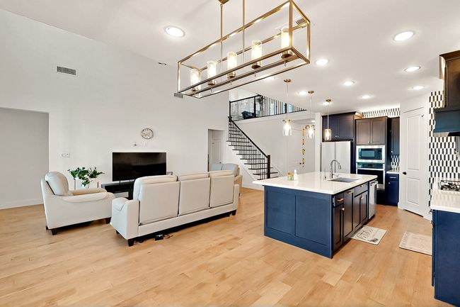 Kitchen featuring stainless steel appliances, a sink, open floor plan, light countertops, and light wood-style floors | Image 10
