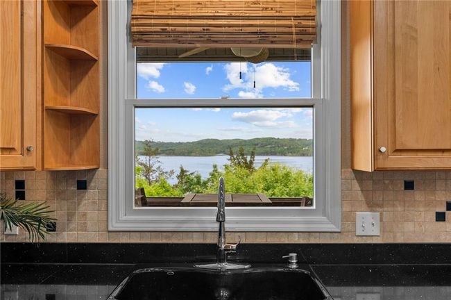 Details featuring dark countertops, decorative backsplash, a water view, and a sink | Image 18