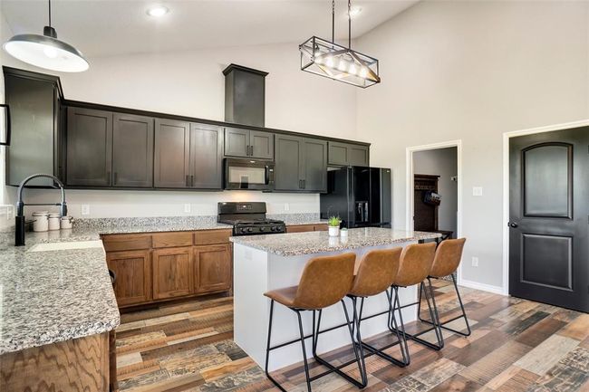 Kitchen with high vaulted ceiling, black appliances, dark wood-type flooring, and a kitchen island | Image 14