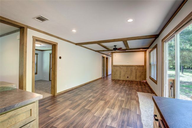 Unfurnished living room featuring a ceiling fan, dark wood-style flooring, plenty of natural light, recessed lighting, and wooden walls | Image 17