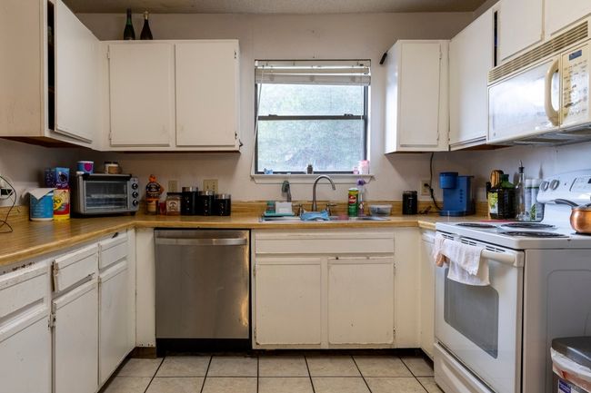 Kitchen featuring white appliances, a sink, white cabinets, and light tile patterned flooring | Image 20