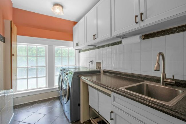 Washroom with washer and dryer, healthy amount of natural light, tile patterned flooring, and cabinet space | Image 26