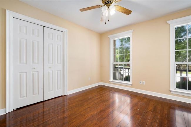 Unfurnished bedroom featuring multiple windows, hardwood / wood-style flooring, a closet, and a ceiling fan | Image 20