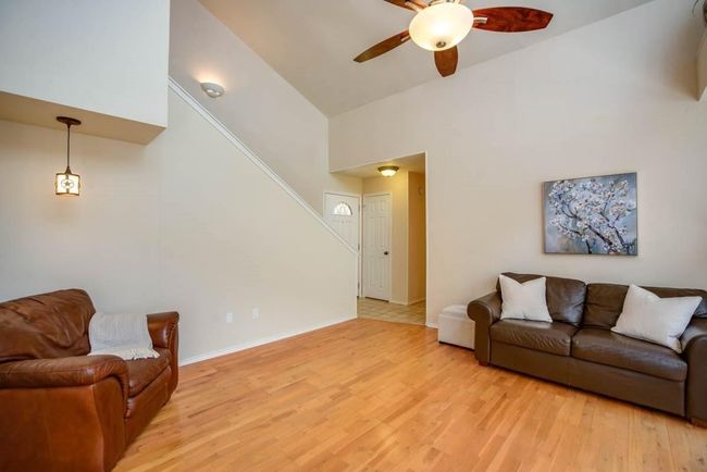 Living area featuring a ceiling fan, light wood-type flooring, stairs, high vaulted ceiling, and baseboards | Image 23