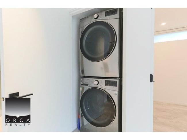 Laundry room featuring stacked washer and clothes dryer and wood finished floors | Image 10