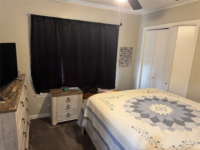 Bedroom with dark colored carpet, ornamental molding, a closet, and ceiling fan | Image 6