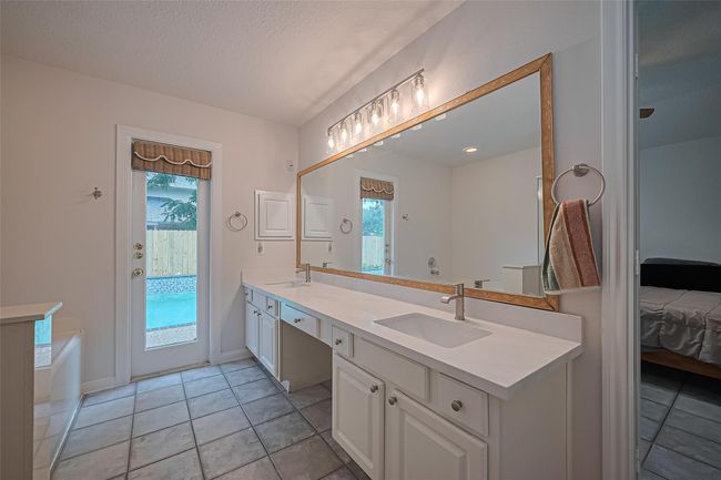 Enjoy a separate jetted soaking tub, updated standalone shower, upgraded quartz countertops, and all-new sinks, faucets, and vanity lights—plus the convenience of a private door leading to the backyard. | Image 21
