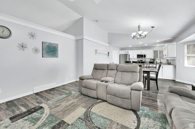 Living area with lofted ceiling, recessed lighting, dark wood-type flooring, baseboards, and a chandelier | Image 10