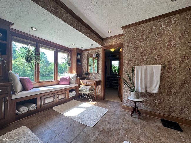 living room featuring crown molding, a textured ceiling, baseboards, wallpapered walls, and plenty of natural light | Image 26