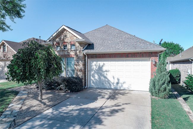 Traditional home featuring roof with shingles, concrete driveway, an attached garage, brick siding, and stone siding | Image 38