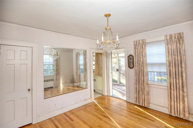 Spare room with a healthy amount of sunlight, an inviting chandelier, ornamental molding, and wood finished floors | Image 5
