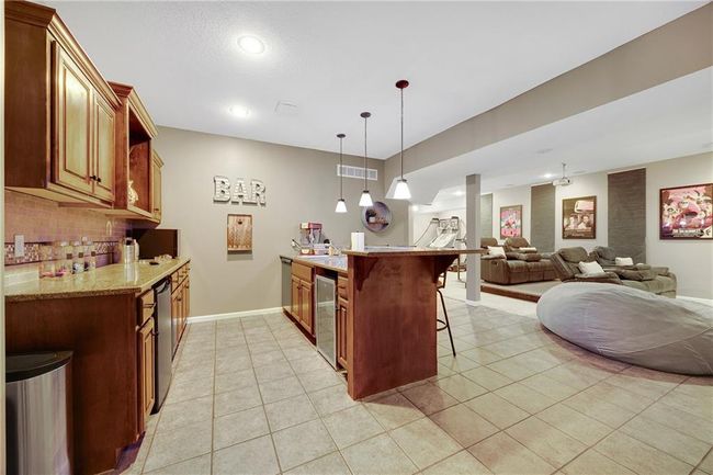 Lower level with a sink, dishwasher, wine fridge, tile backplash and granite counter tops. | Image 39