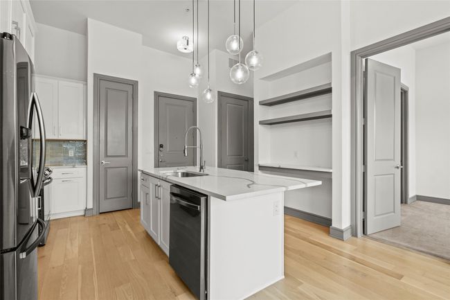 Kitchen with a sink, dishwashing machine, stainless steel fridge, and white cabinetry | Image 13