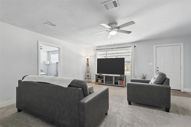 Carpeted living area featuring a ceiling fan, a textured ceiling, and baseboards | Image 23