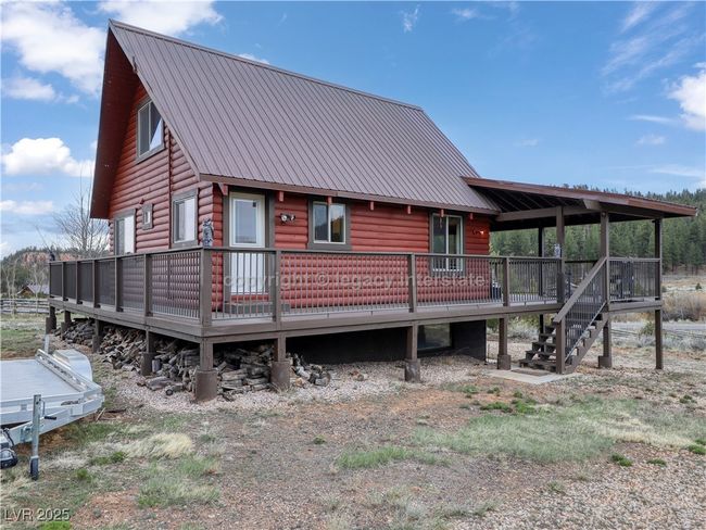 Rear view of property featuring stairway, faux log siding, a deck, and metal roof | Image 48