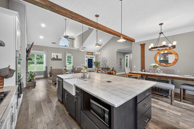 Kitchen with open floor plan, stainless steel appliances, ceiling fan, dark cabinetry, and decorative light fixtures | Image 12