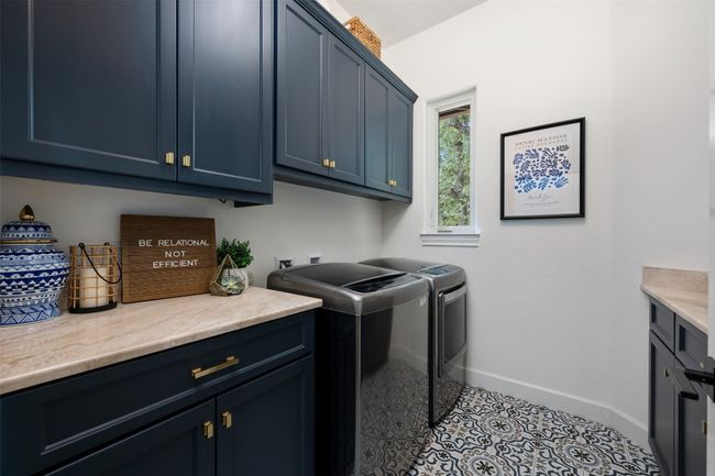 Oversized utility room with an abundance of cabinet and counter space along with decorative tile floor. | Image 22