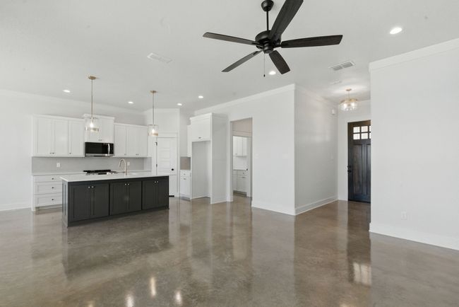 Kitchen with stainless steel microwave, concrete floors, baseboards, white cabinets, and crown molding | Image 4