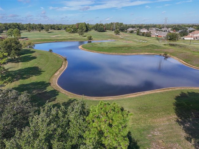 This view is located right out front of the home. Windrose Golf Course hole #10 serene, expansive landscape featuring a large pond and lush green surroundings. Offering a peaceful, scenic view with a suburban feel. Ideal for those seeking tranquility and natural beauty. | Image 32
