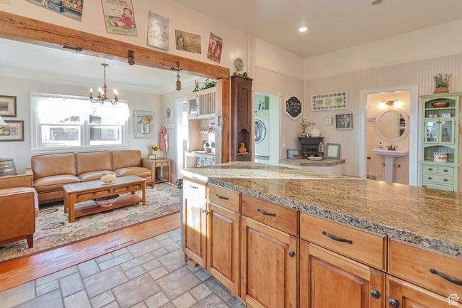 Kitchen featuring light stone counters, pendant lighting, a notable chandelier, and washer / clothes dryer | Image 35