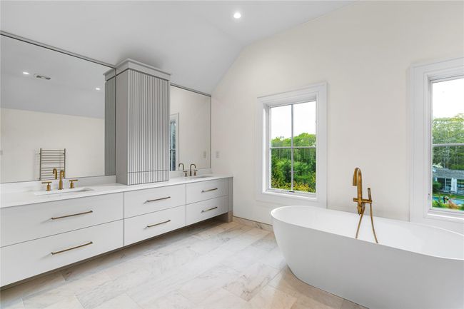 Full bathroom featuring double vanity, a freestanding tub, lofted ceiling, marble look tile flooring, and recessed lighting | Image 35
