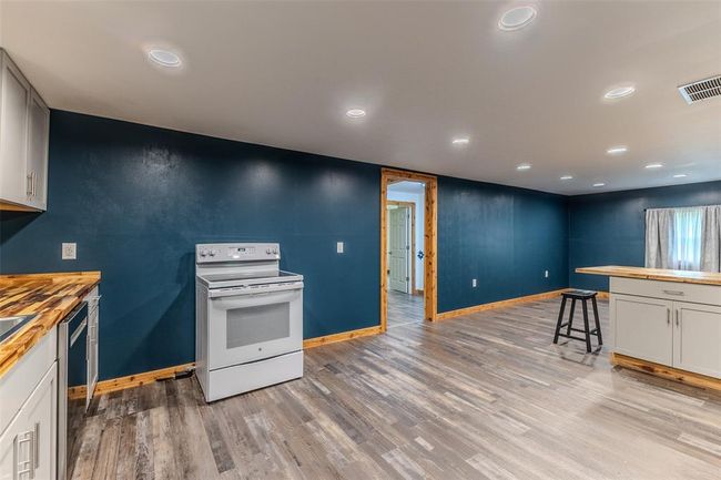 Kitchen with white electric range, butcher block counters, baseboards, light wood-style flooring, and recessed lighting | Image 11