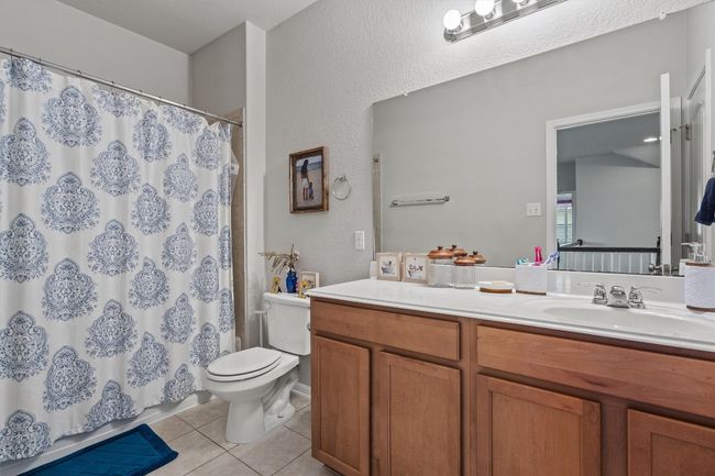 Bathroom featuring tile patterned floors, toilet, vanity, a textured wall, and a shower with curtain | Image 30