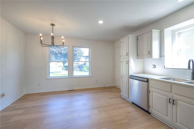 Kitchen with dishwasher, a chandelier, light wood-style floors, white cabinets, and recessed lighting | Image 8