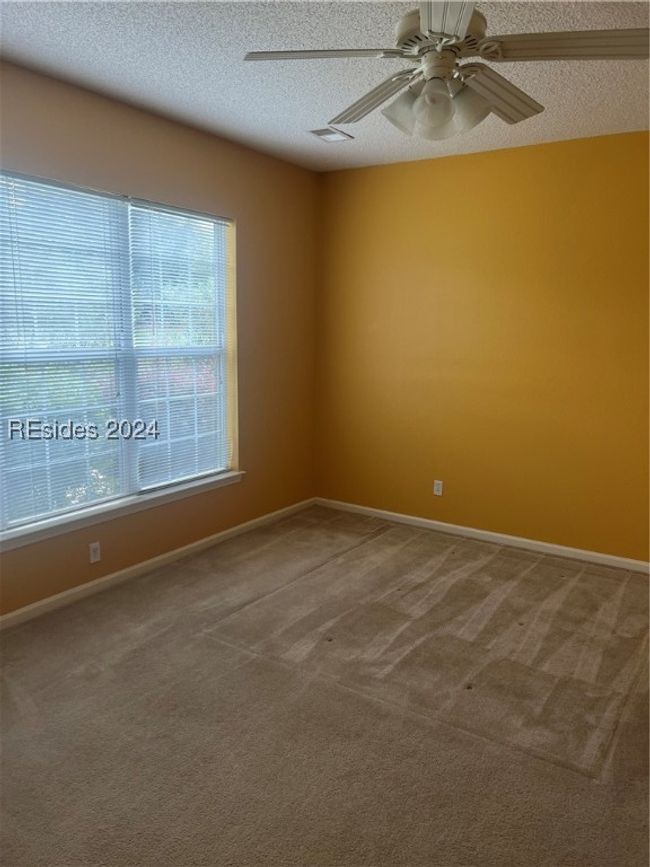 Carpeted empty room with a textured ceiling and ceiling fan | Image 17