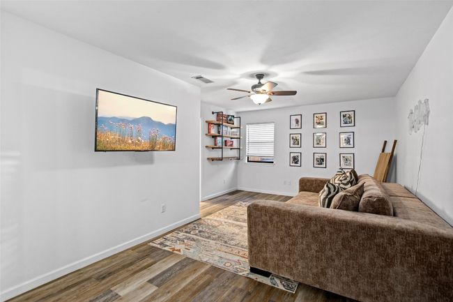 Living room with wood finished floors, a ceiling fan, and baseboards | Image 26