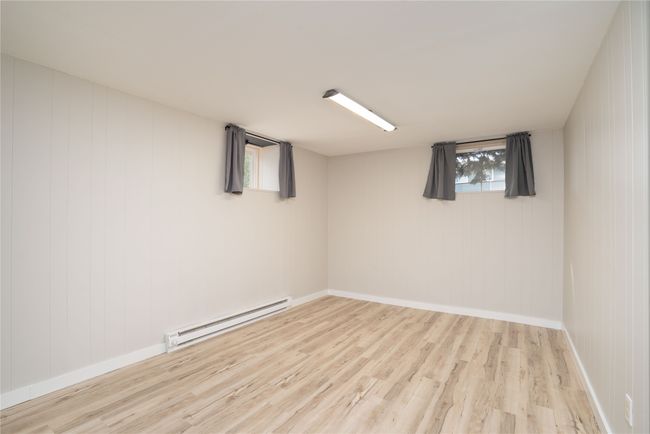 Basement with a baseboard radiator, wood finished floors, and baseboards | Image 23