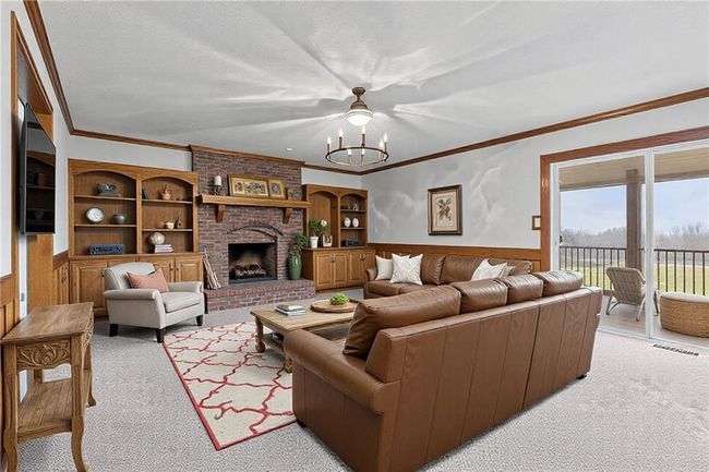Living room with a wainscoted wall, a fireplace, a chandelier, and crown molding | Image 7