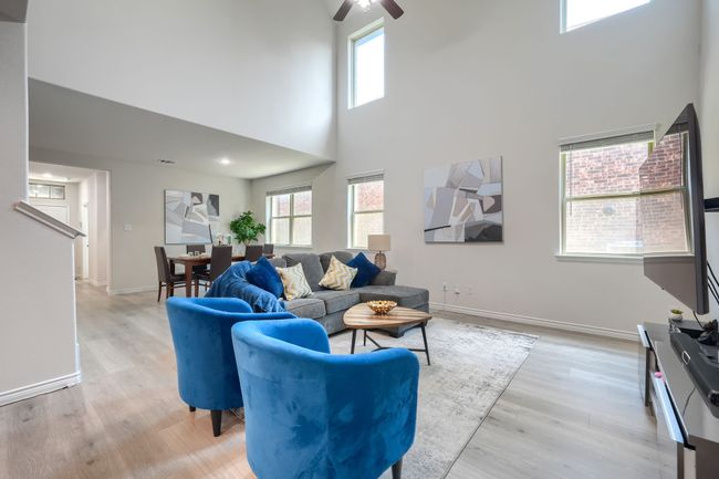 Living room featuring a high ceiling, a ceiling fan, light wood-style floors, and baseboards | Image 8
