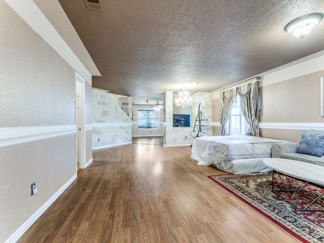 Bedroom featuring a textured ceiling, a chandelier, and wood finished floors | Image 12