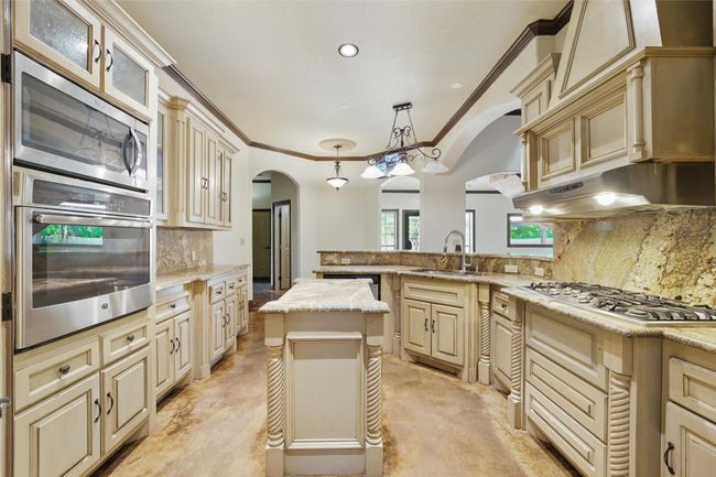 Kitchen with stainless steel appliances, arched walkways, cream cabinetry, ornamental molding, and recessed lighting | Image 12