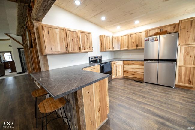 kitchen with a peninsula, dark wood-style floors, lofted ceiling, appliances with stainless steel finishes, and light brown cabinetry | Image 6