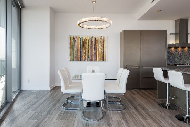 Dining room with designer chandelier and balcony access. | Image 18